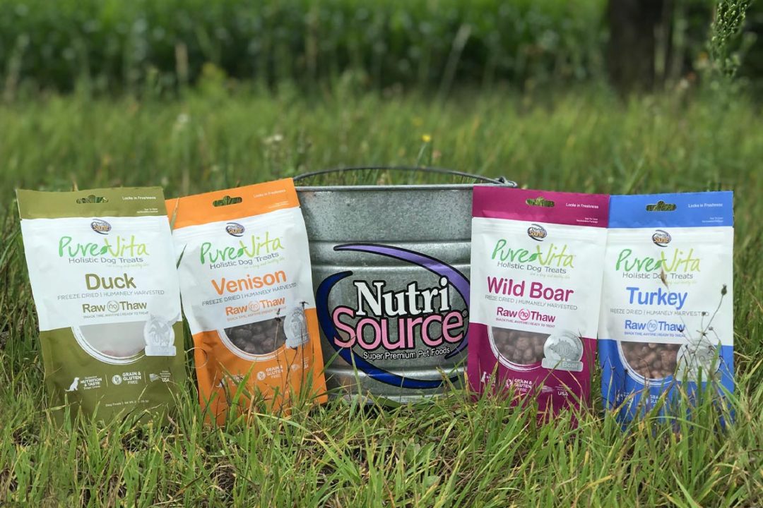 NutriSource bucket on grass surrounded by PureVita dog treats