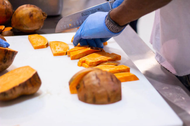 NomNomNow employee cuts sweet potatoes for fresh pet food production
